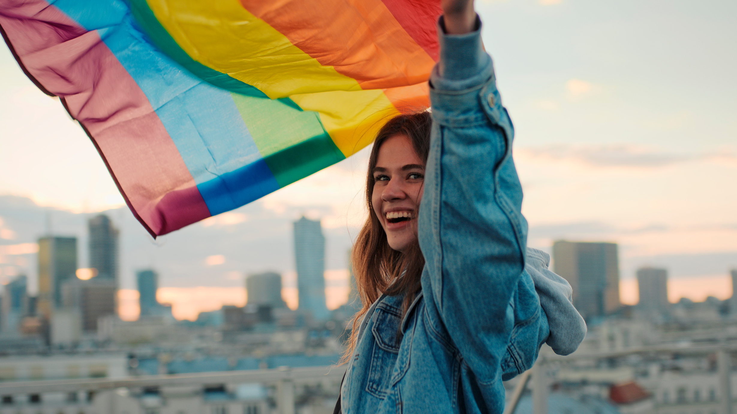 LGBT proud. Happy woman holding lgbt flag. Rooftop view